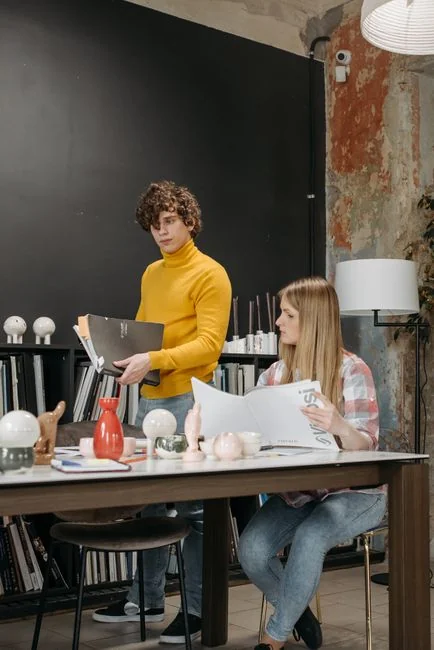 Moderní pracovní prostor s dvojicí počítačových monitorů zobrazujících webové designové projekty, který zdůrazňuje technologie a produktivitu.